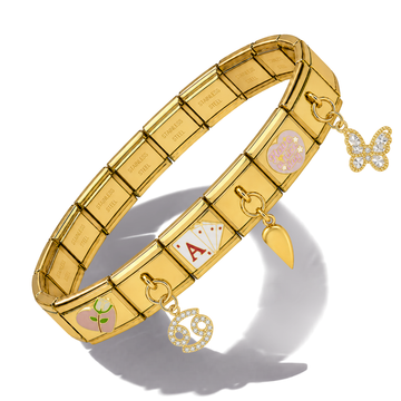 Gold-tone elastic name bracelet with engraved names on each link, decorated with three charms: a butterfly, a heart with pink enamel and white stones, and a heart with a green rose and white stones. The bracelet is displayed on a clean white background with a soft shadow.