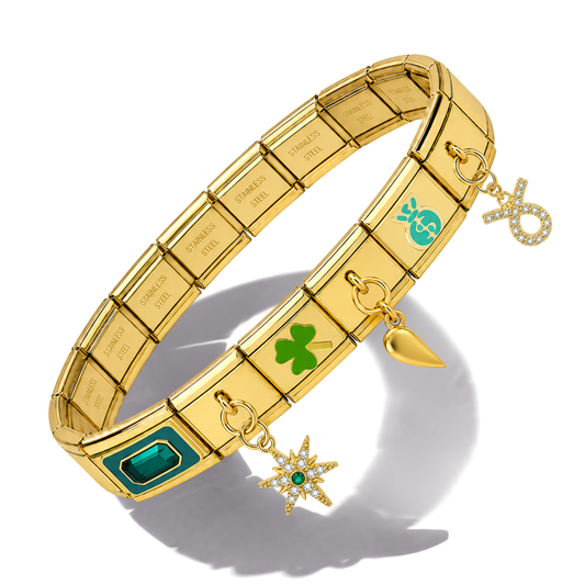 A gold-toned segmented charm bracelet with green enamel accents, crystal details, and multiple dangling charms including a shamrock, star, heart, and infinity symbol, shown on a white background.